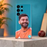 Virat Kohli smiling in an orange training shirt on a teal mobile skin, teal studio hero