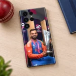 Virat Kohli T20 trophy mobile skin on a wooden desk beside a cricket ball