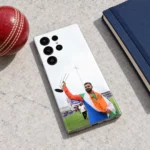 Virat Kohli raising a silver trophy while draped in the Indian tricolour on a mobile skin, cricket table flat lay