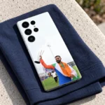 Virat Kohli raising a silver trophy while draped in the Indian tricolour on a mobile skin, navy fabric lifestyle