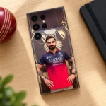 Virat Kohli mobile skin with red jersey portrait and gold lion backdrop, oak desk flat lay