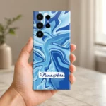 Ocean Wave Abstract Customized Name Mobile Skin — in hand showing cyan and cobalt flowing waves with a white brushstroke sample name label
