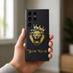 Royal Lion Crown Customized Name Mobile Skin — in hand showing a gold crowned lion on charcoal with ornate gold sample name lettering