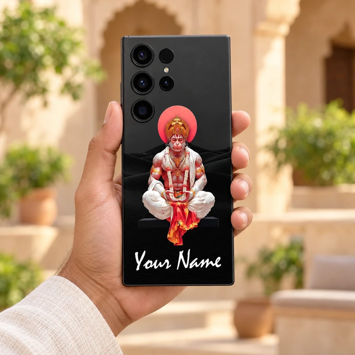 Hanumanji Meditation Custom Name Mobile Skin - Courtyard handheld Hanumanji meditation phone skin held in hand with white sample name below devotional artwork