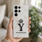 Royal White Marble Custom Name Mobile Skin — in hand showing white marble with a black crown, Y monogram and sample name